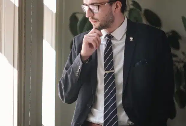 a man in a suit and tie standing in front of a window